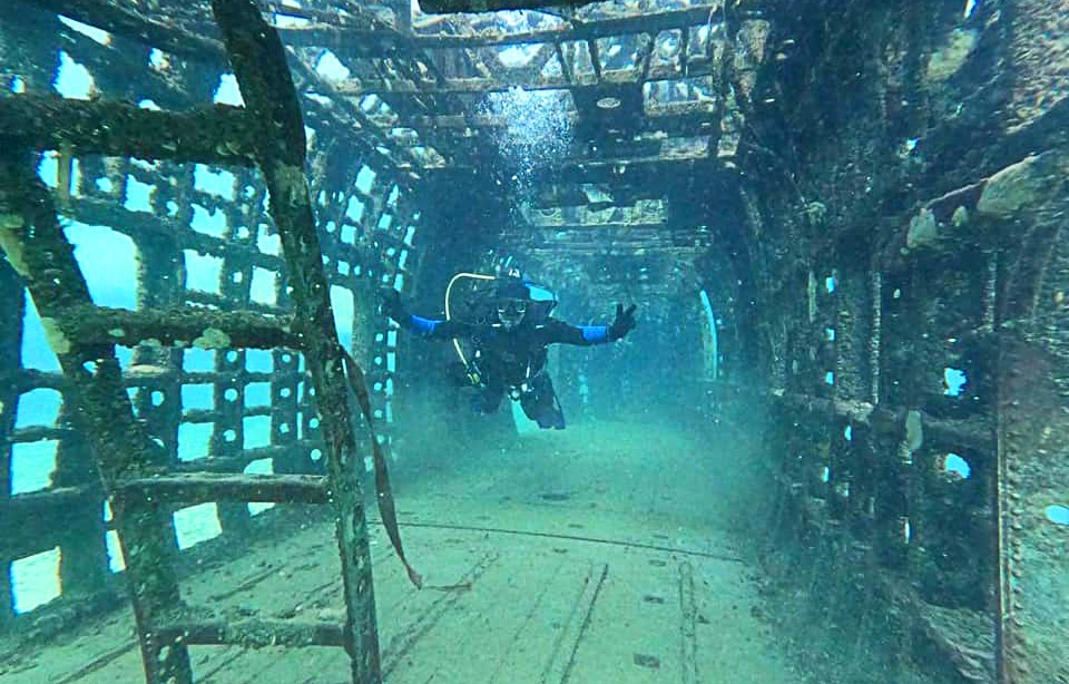 horizontal photo of a scuba diver exploring inside one of the wrecks in Gilboa Quarry