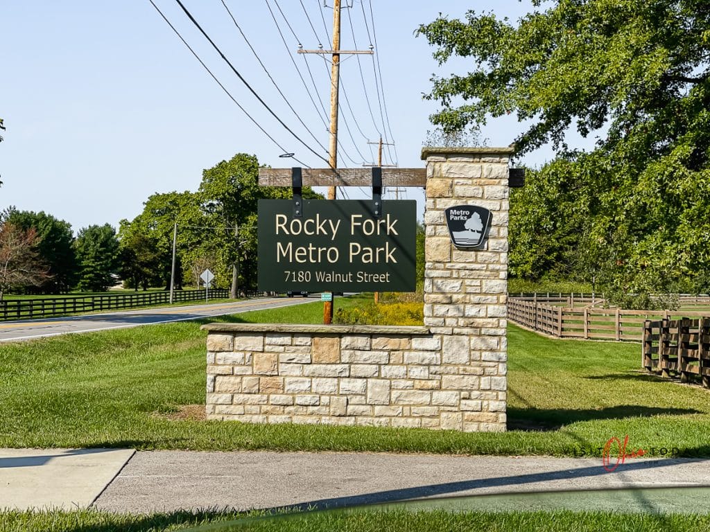 side of a street with a stone and brown sign that reads rocky fork metro park