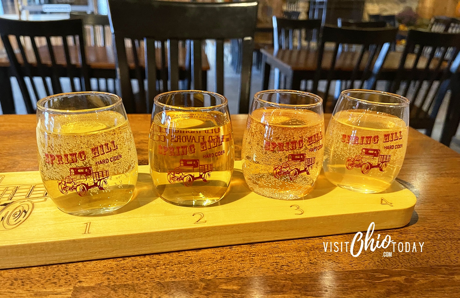 horizontal photo of 4 small glasses of spring hill winery ciders on a wooden board Photo credit: Cindy Gordon of VisitOhioToday.com