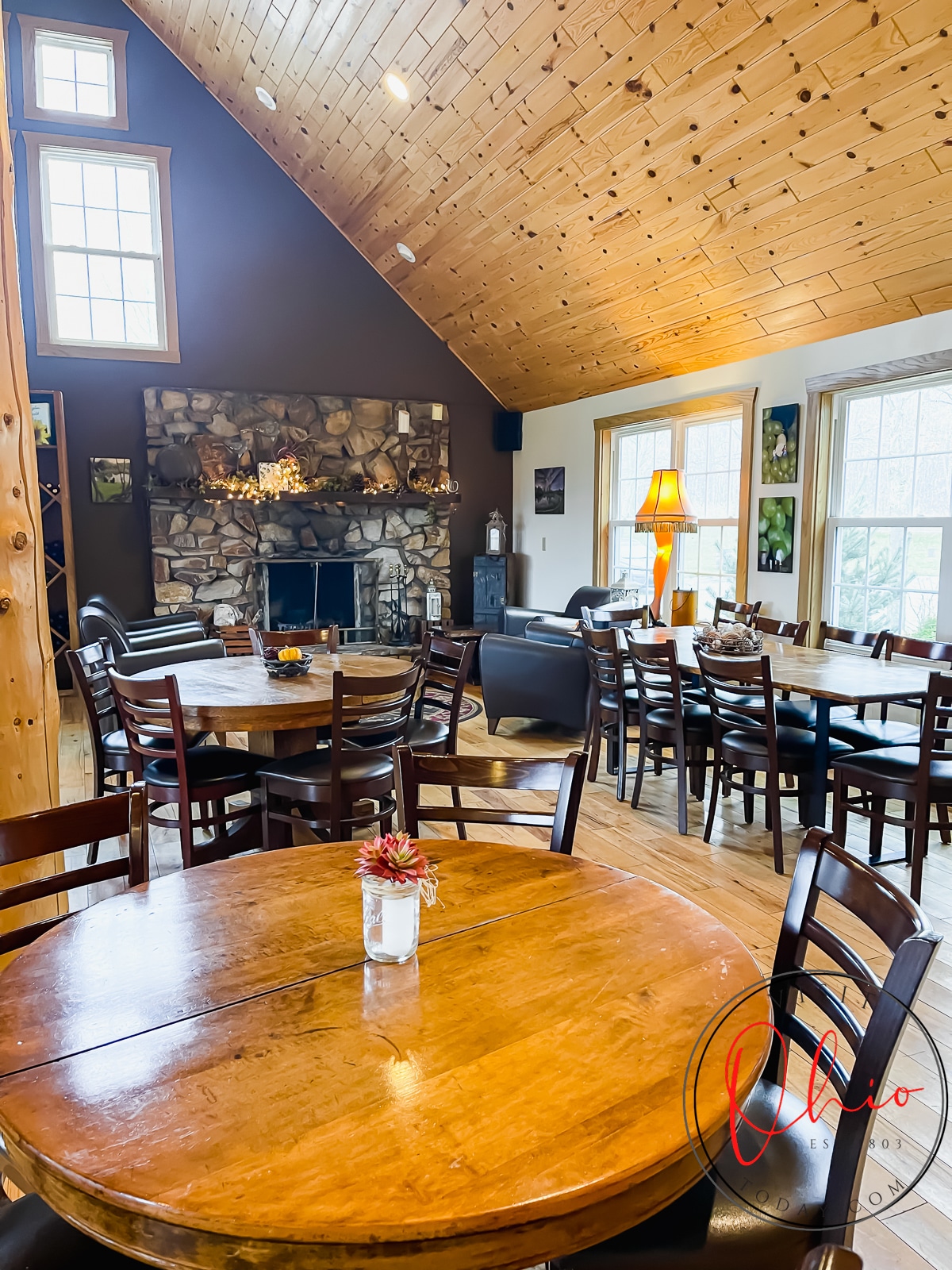 vertical photo of dinning room with wood round tables and black chairs, stone fireplace in far background Photo credit: Cindy Gordon of VisitOhioToday.com