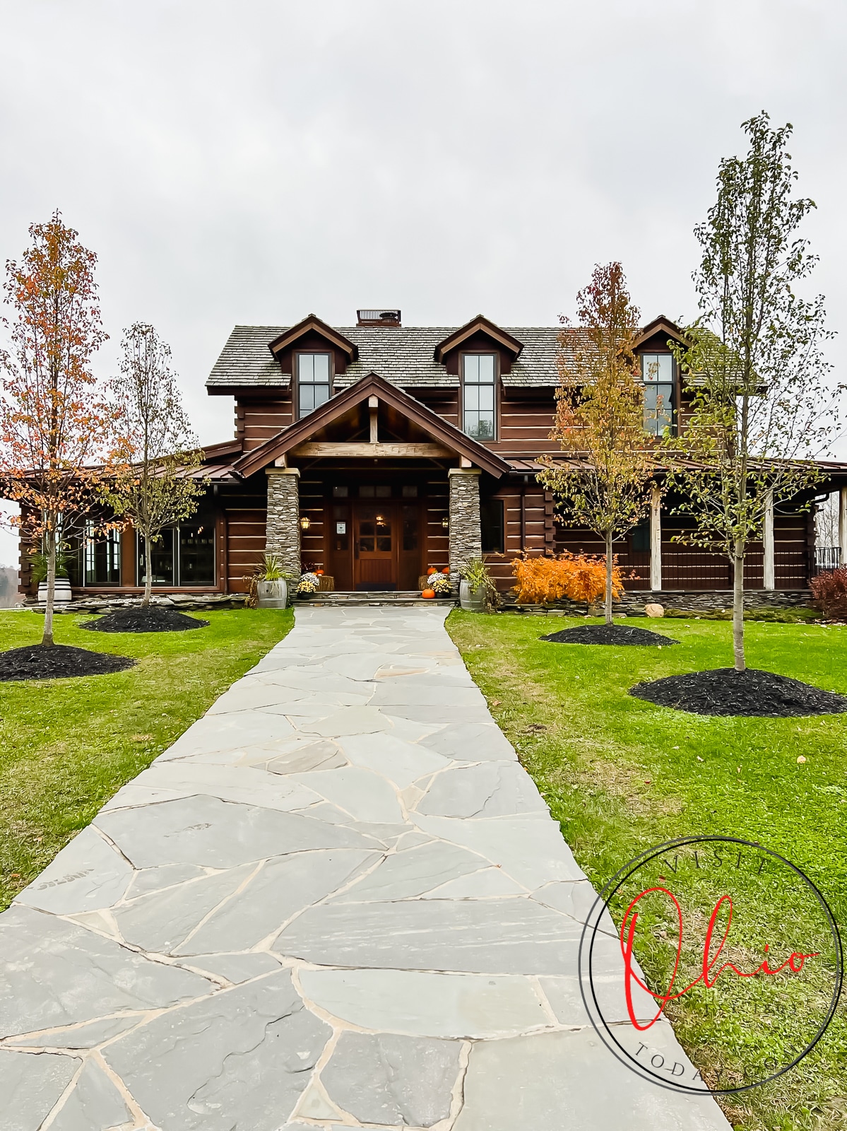 pictured is a log cabin with stone entry way, trees with orange leaves and a stone side walk leading up to building Photo credit: Cindy Gordon of VisitOhioToday.com