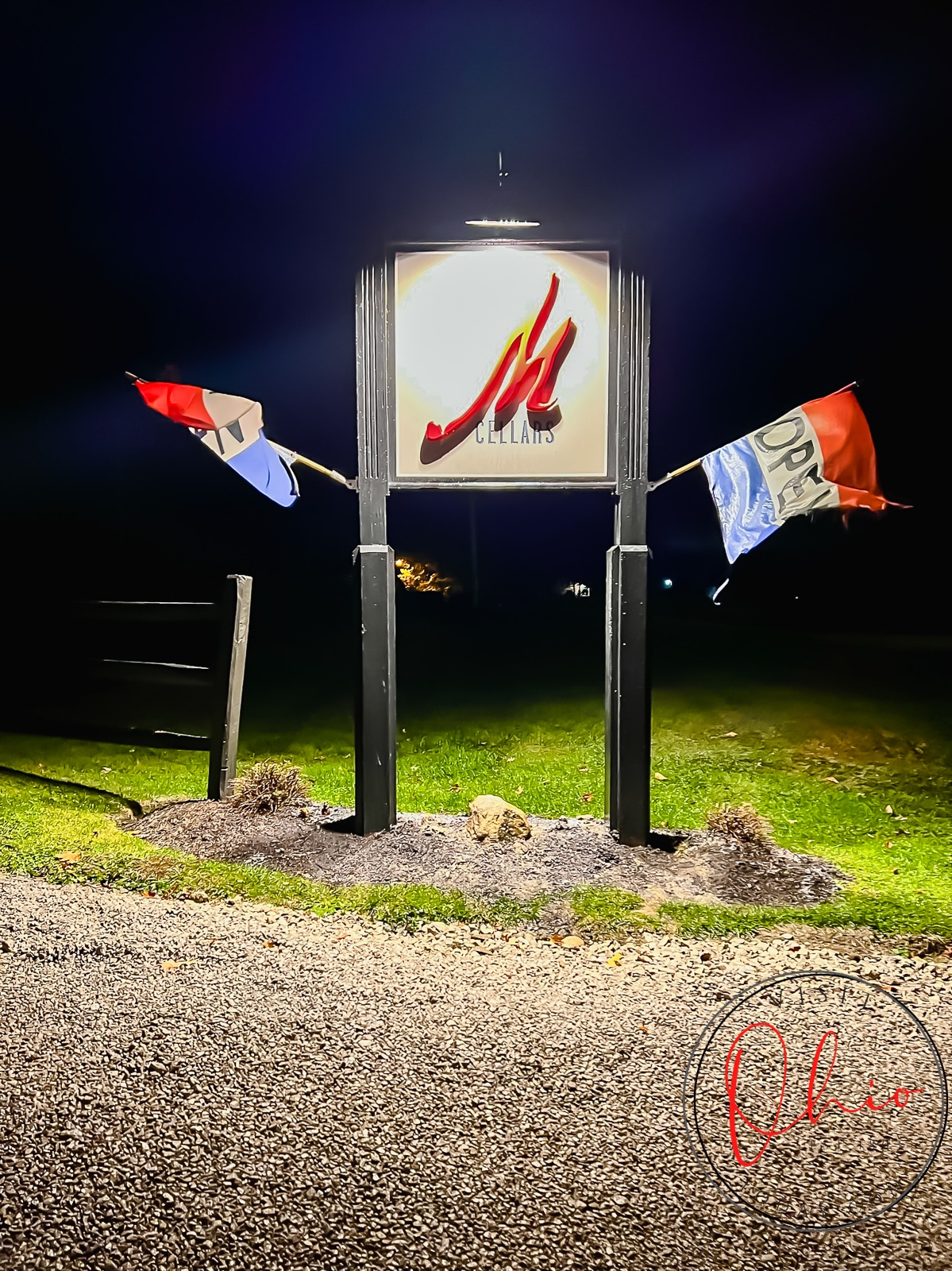 M Cellars sign in the dark, lit up by lights. Has two open flags on the left and right Photo credit: Cindy Gordon of VisitOhioToday.com