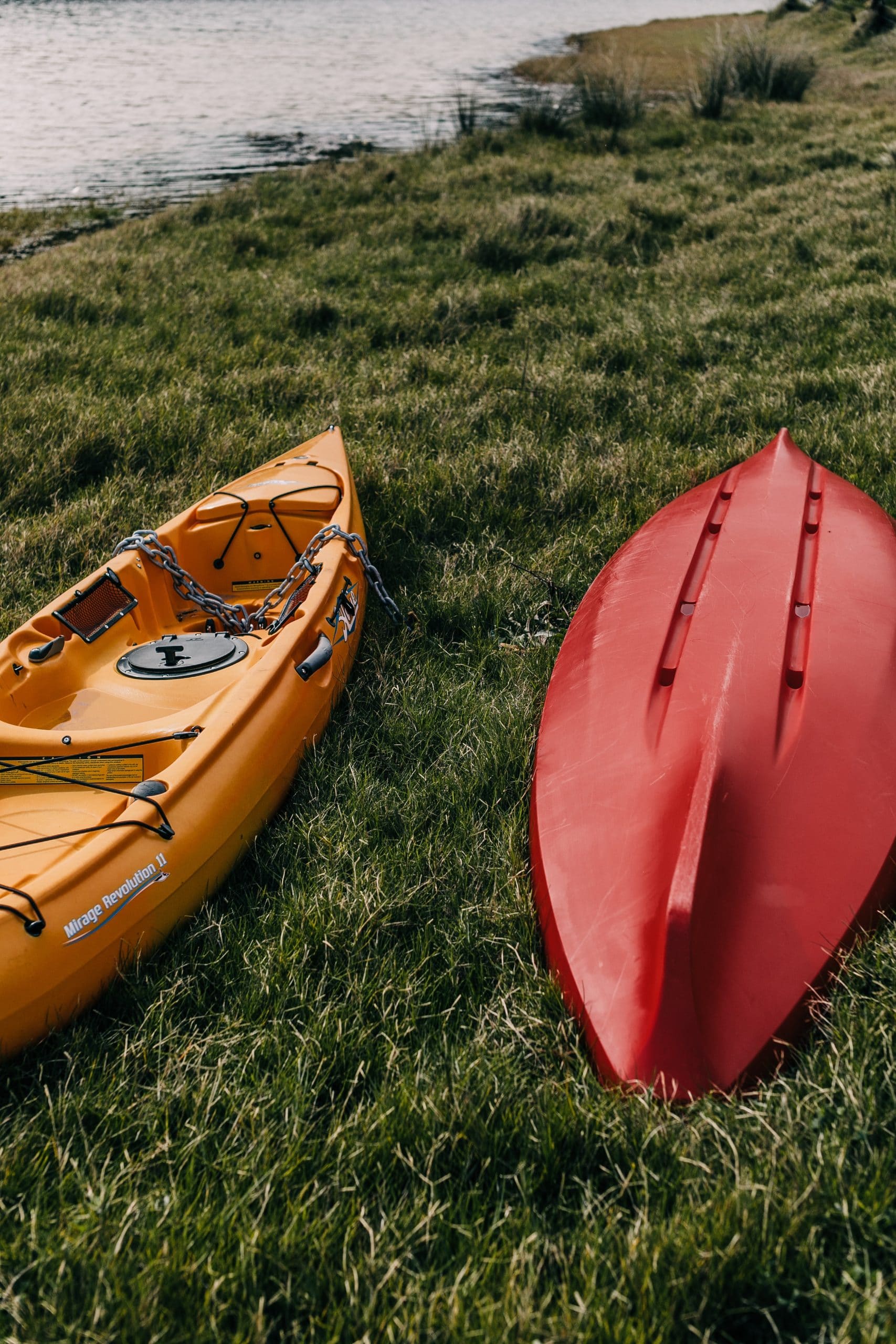 picture of orange kayak and red kayak on green grass