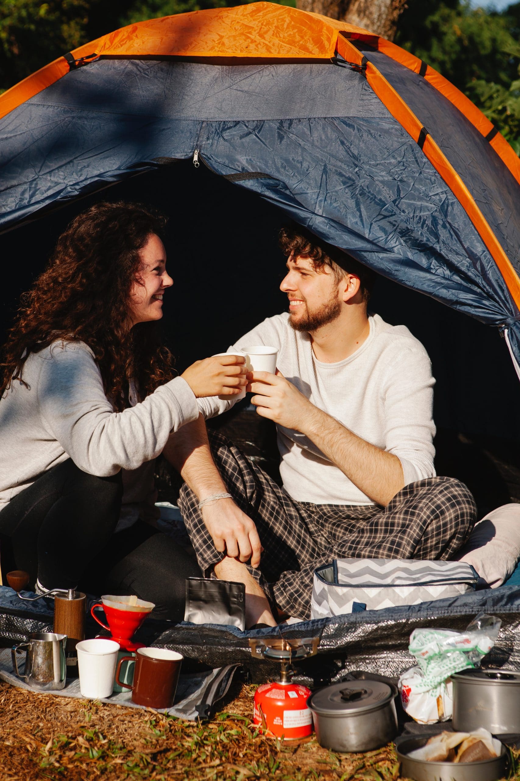 man and lady toasting with coffee cups in a tent.
