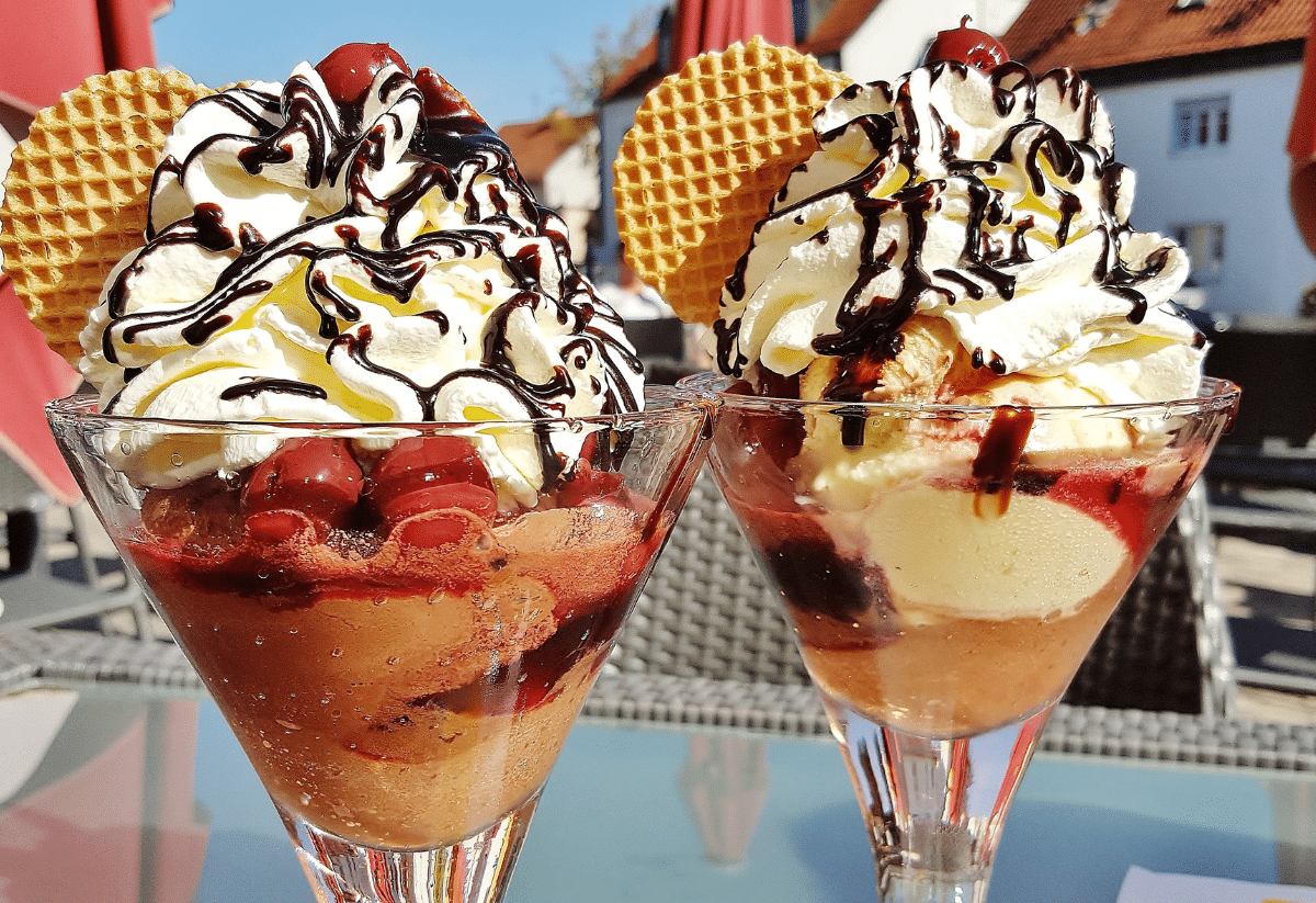 horizontal photo of two ice cream sundaes on a glass table