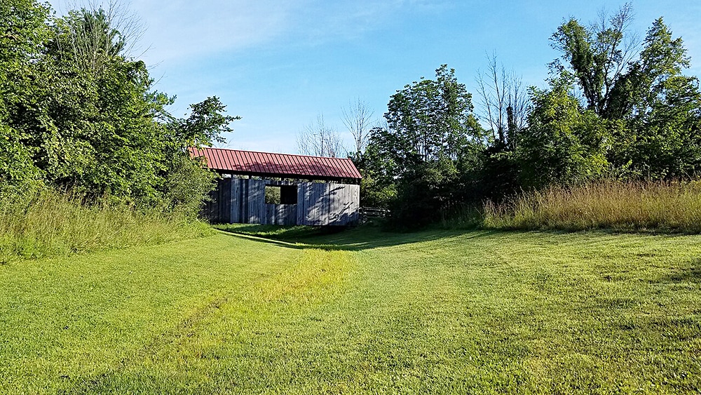 horizontal photo of one of the buildings at the Slate Run Historical Farm, with grass in the foreground