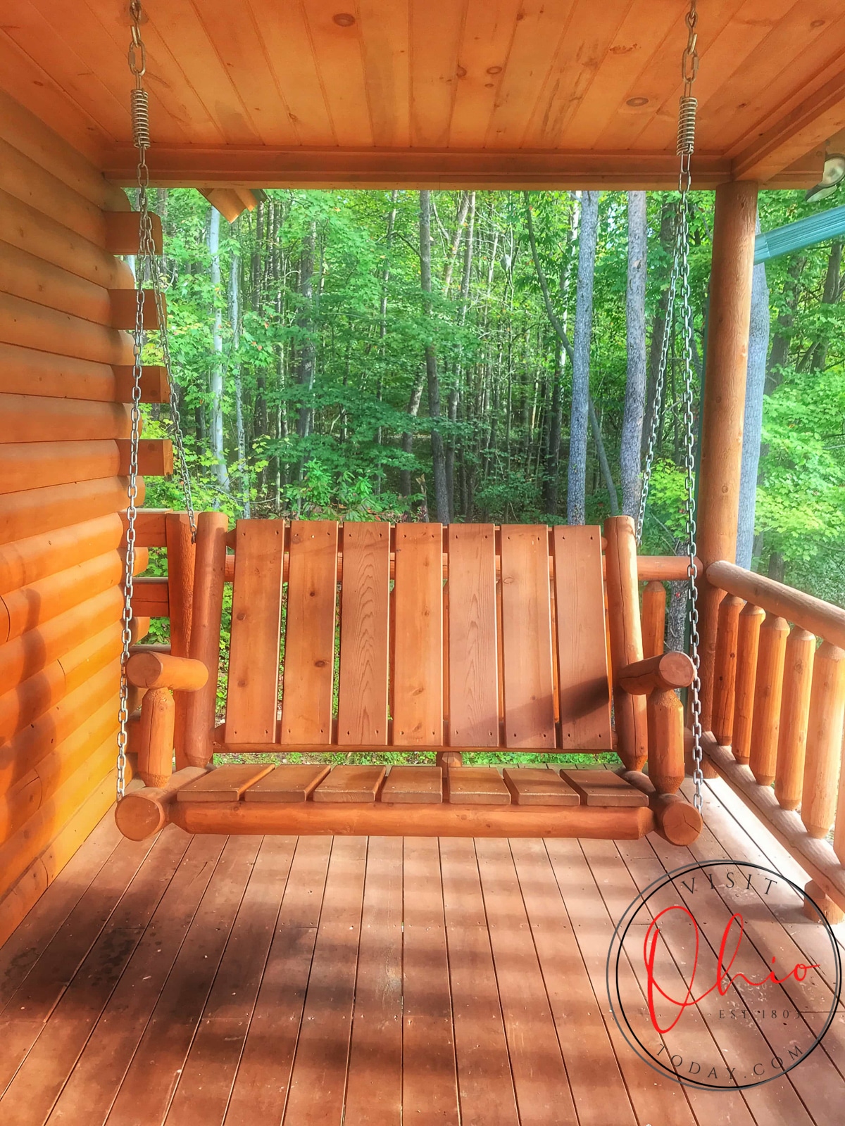 brown swing on deck with green trees and leaves behind it at cedar grove lodging