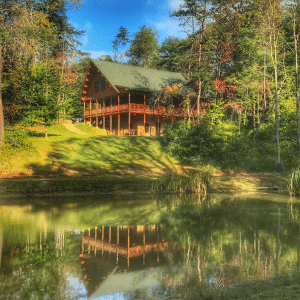 heavily edited picture of still water lodge cabin with greens and browns and the relfection in a pond