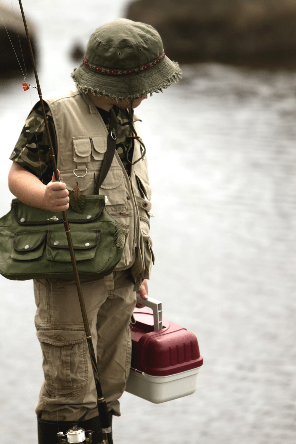child fisherman with fishing poll, vest, hat and tackle box