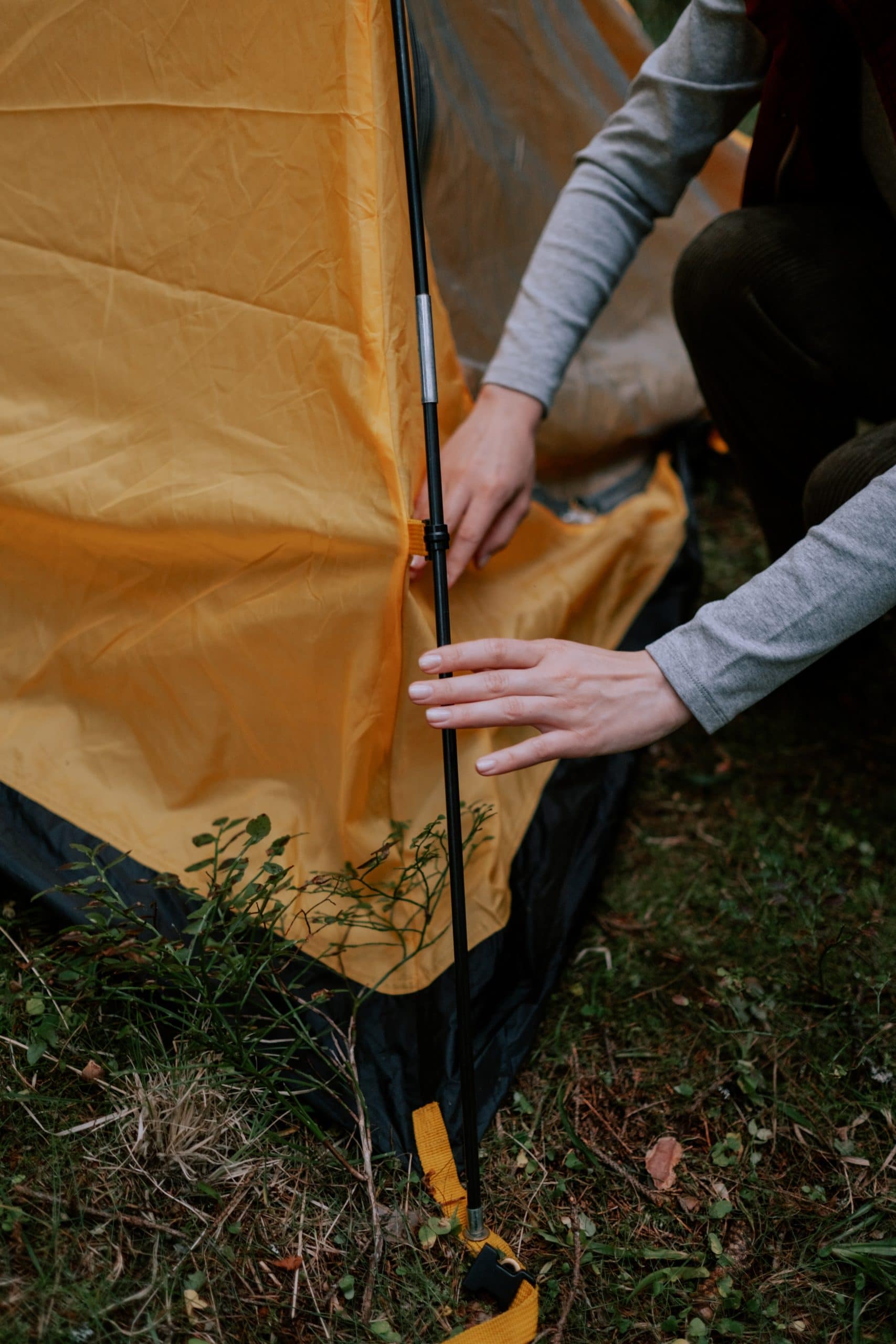 yellow pop up tent with female putting pole in side of tent