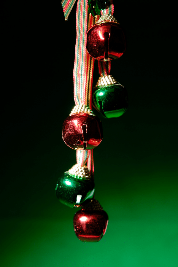 Green background with red and green metal jingle bells on gold string
