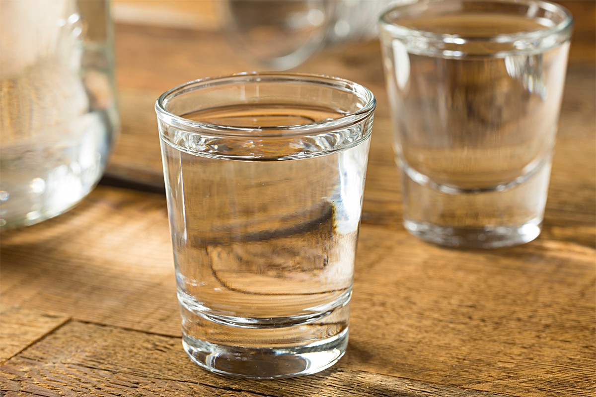 horizontal photo of two shot glasses with Moonshine on a wooden surface