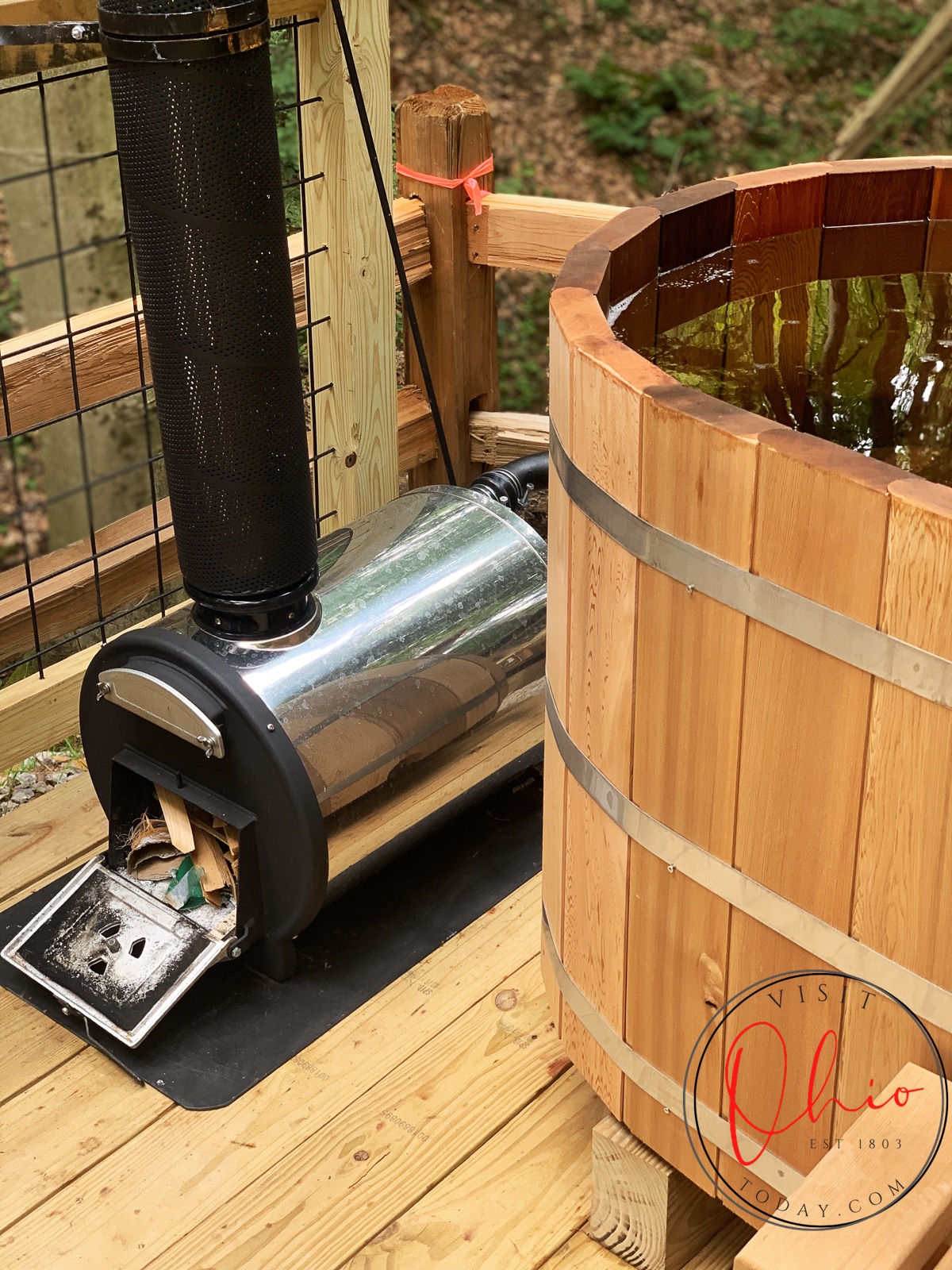 cedar oval tub full of water sitting on wooden deck with a black and silver tank with kindling in it Photo credit: Cindy Gordon of VisitOhioToday.com