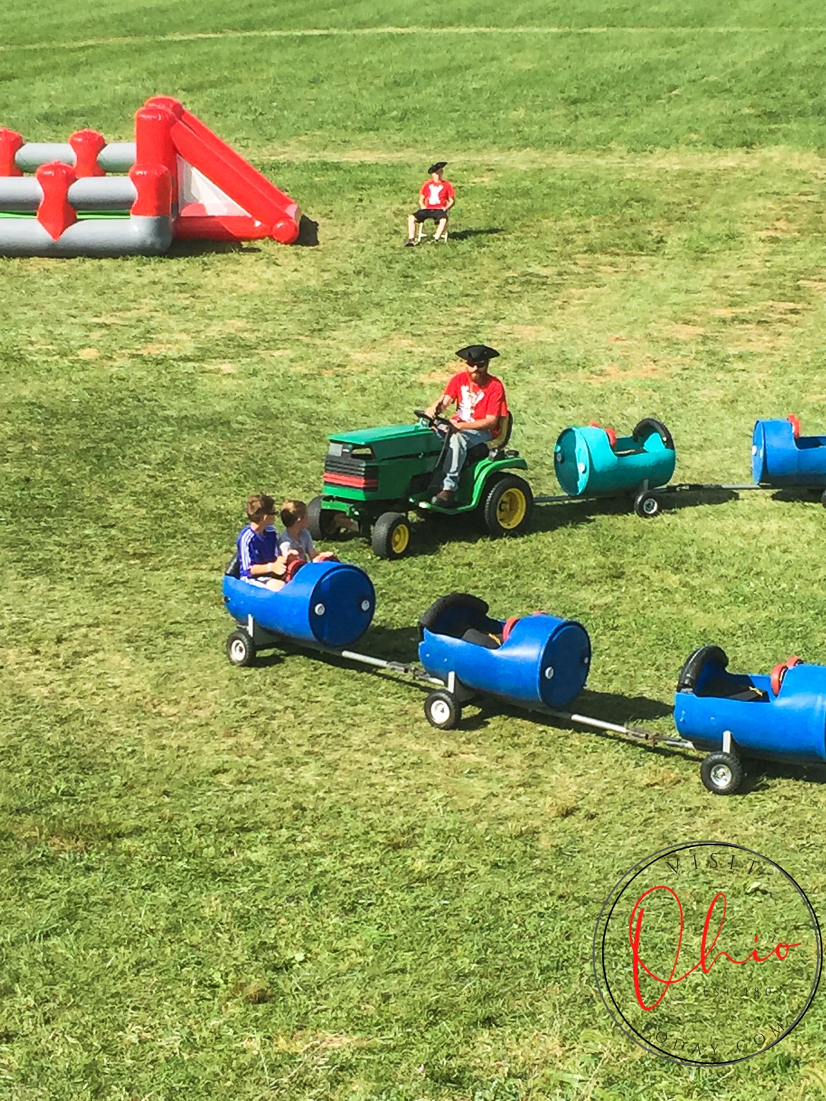 barrel train, can see driver on tractor and two kids in a barrel cart
