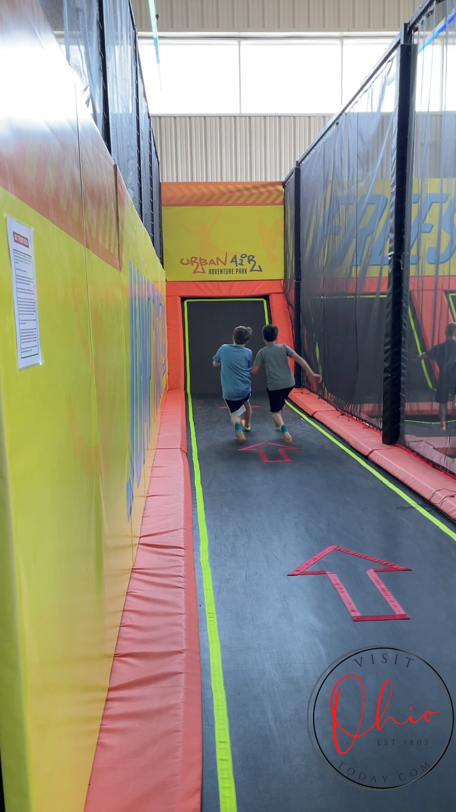two boys running down a long skinny trampoline