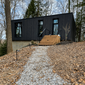 Idyll Reserve - The Hillside at top of picture. Black building with wooden steps, gravel path leading to cabin