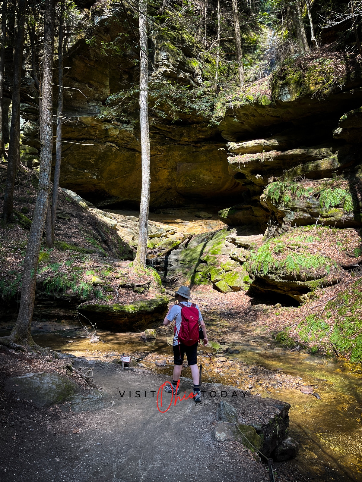 man with hat and red backpack walking a path into the forest Photo credit: Cindy Gordon of VisitOhioToday.com