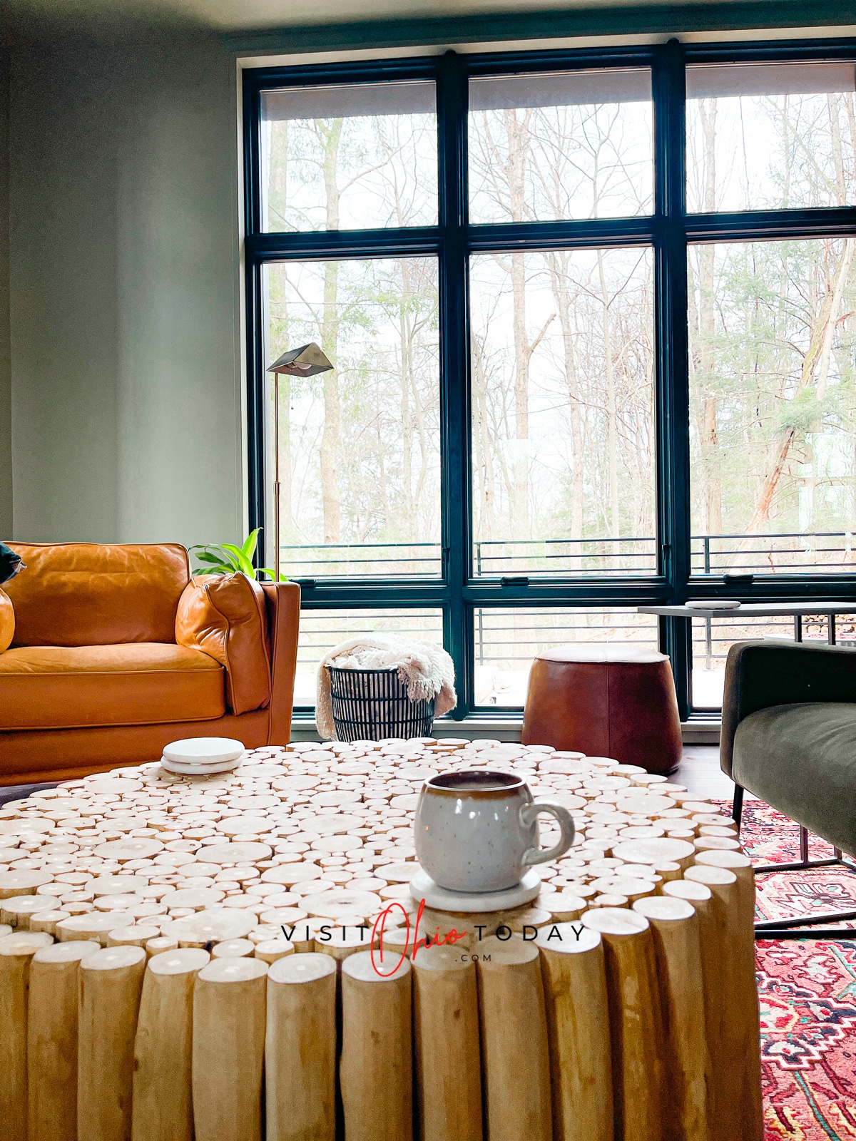 orange leather chair to left, wooden stick coffee table, wall of windows Photo credit: Cindy Gordon of VisitOhioToday.com