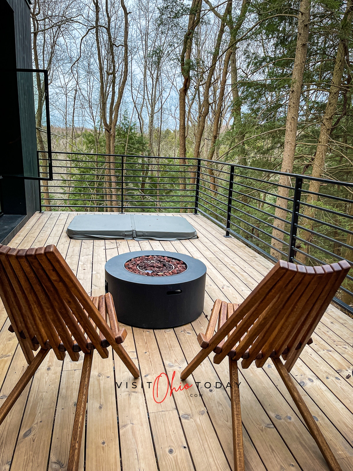 wooden deck with wire decking, sunken hottub with grey lid, gas fireplace and two wooden chairs Photo credit: Cindy Gordon of VisitOhioToday.com