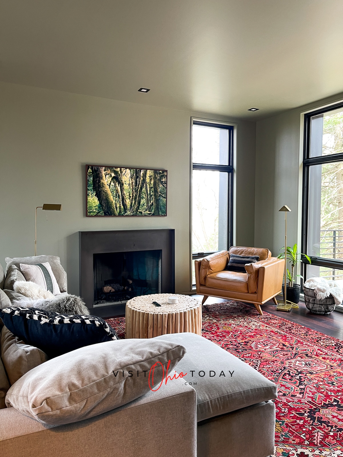 painting and fireplace on wall, couch with lots of pillows, red rug and leather chair to the side Photo credit: Cindy Gordon of VisitOhioToday.com