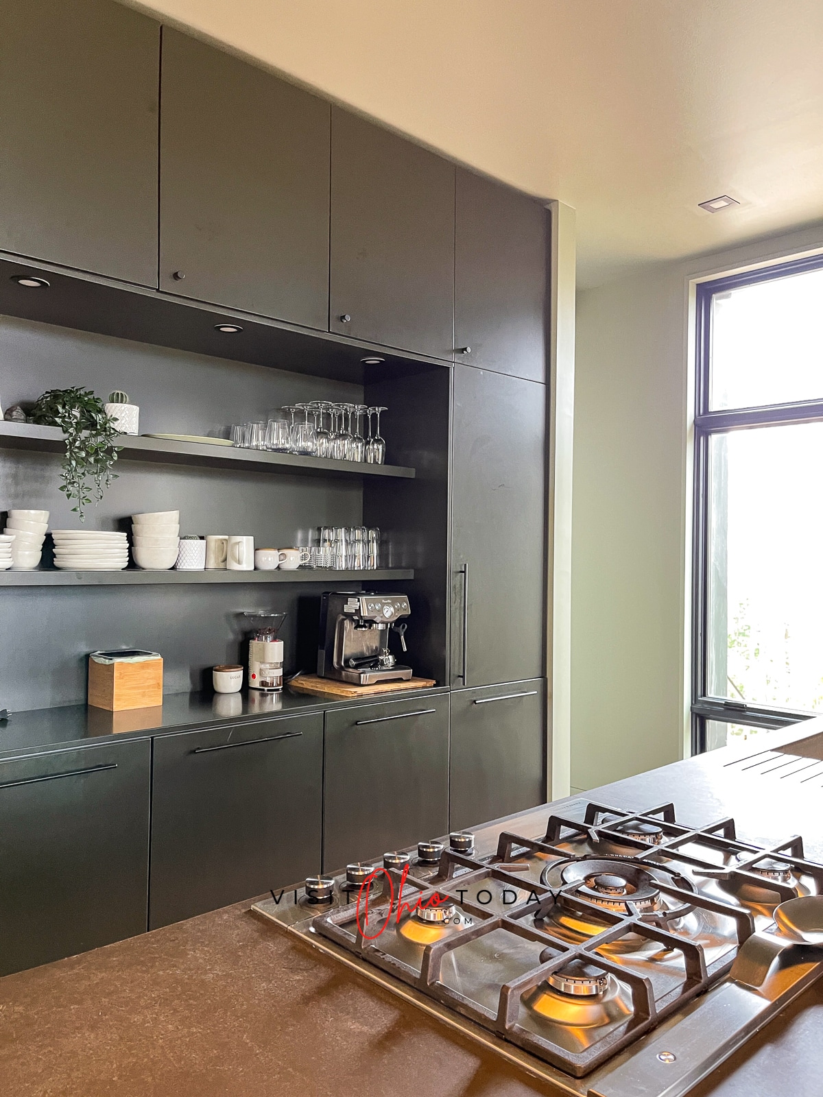 green cabinet kitchen at Idyll Reserve - The Hillside feature open shelves with white dishes on it and gas stove on island Photo credit: Cindy Gordon of VisitOhioToday.com