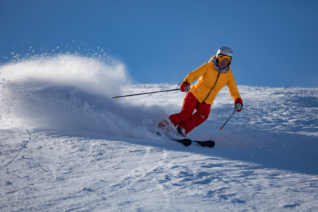 Someone skiing wearing brightly coloured clothes, Blue sky and powdery white snow