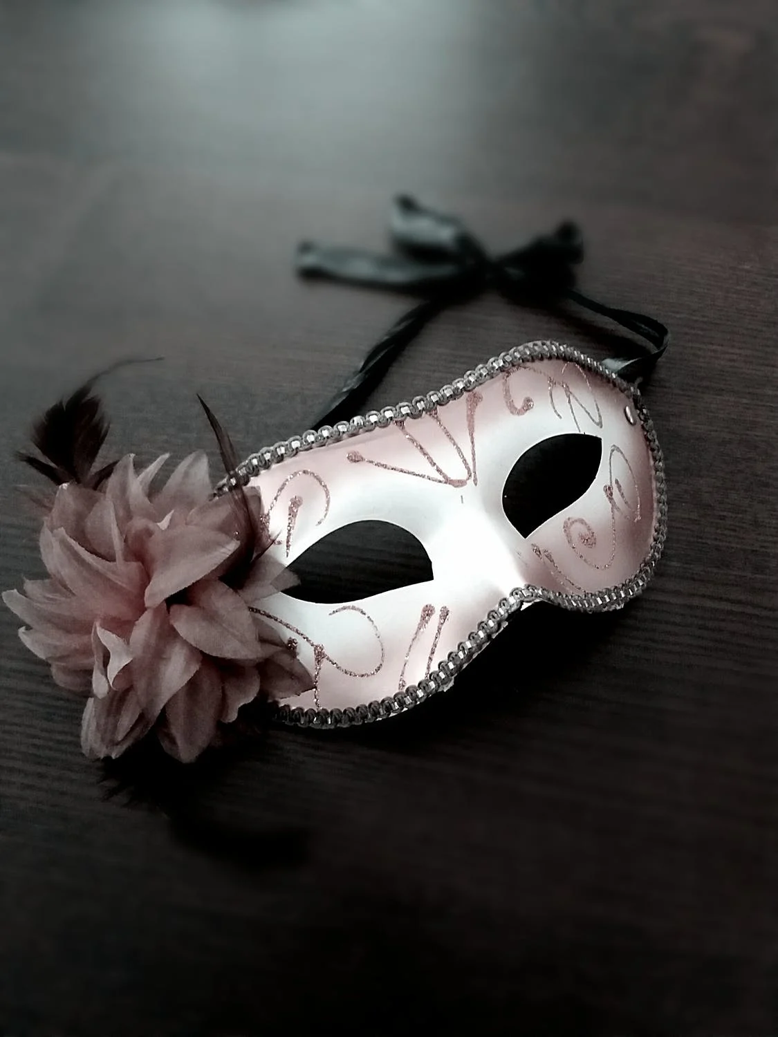 A white opera mask on a black table