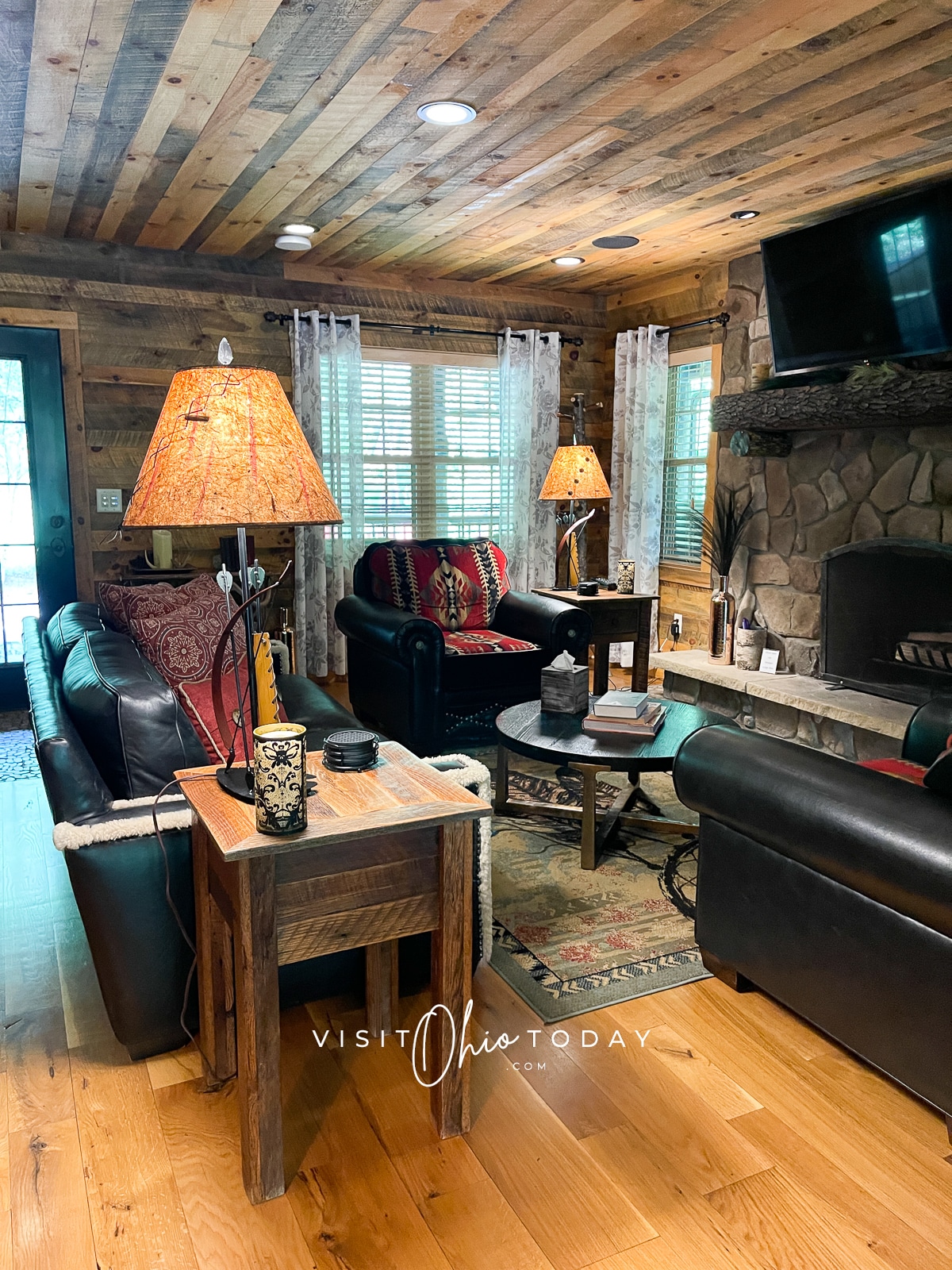 dark wood walls and ceiling with black leather couch and two chairs with two lights and a fireplace Photo credit: Cindy Gordon of VisitOhioToday.com