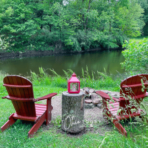 red chairs in front of a pond with green grass and trees