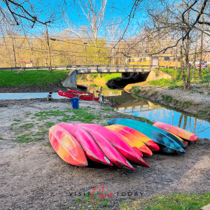 pink and orange kayaks on gravel with blue sky in back