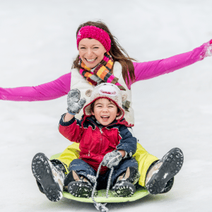 A woman and a child on a sled in snow
