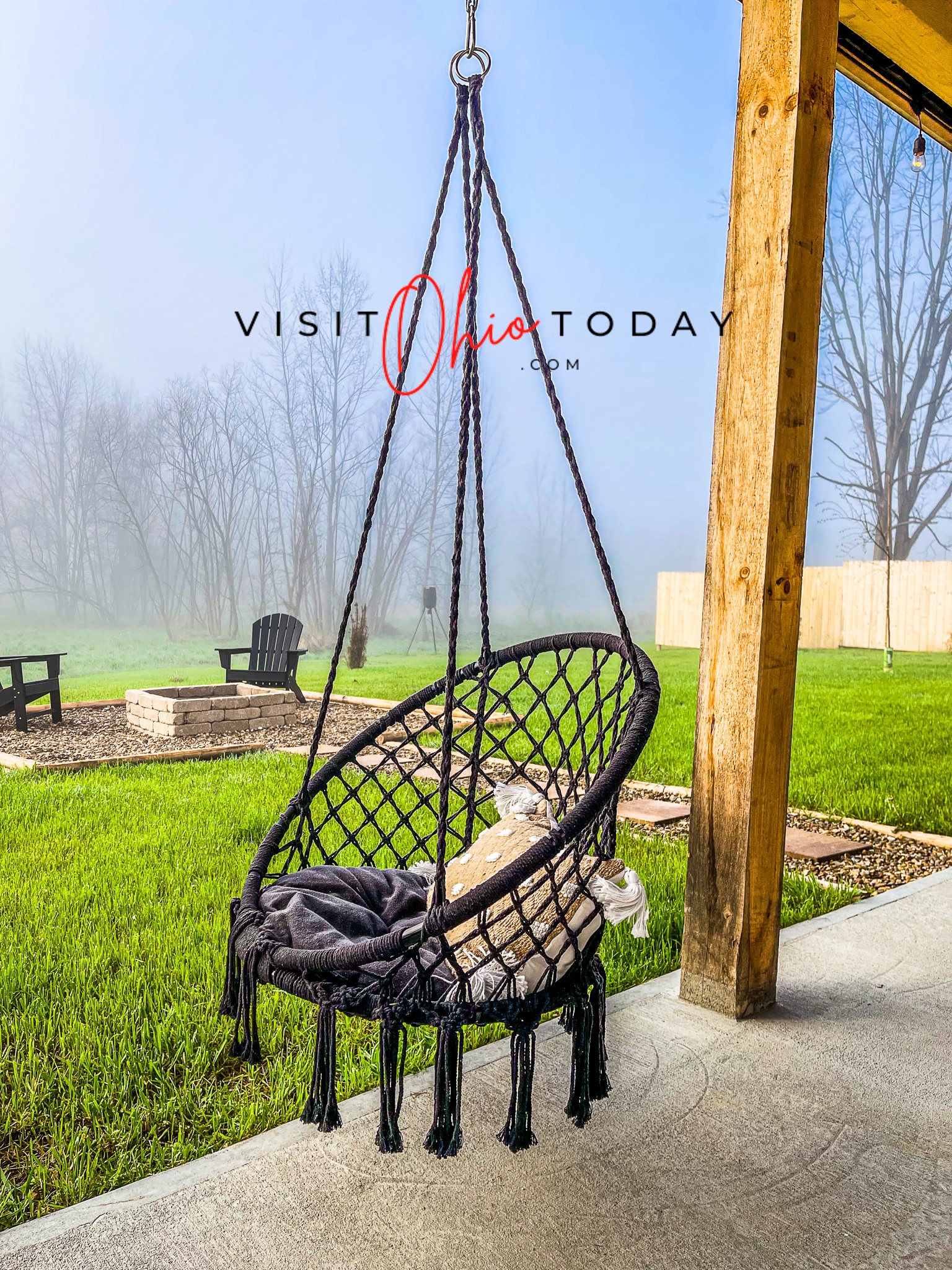 hanging rope chair in front of green grass and fire pit area