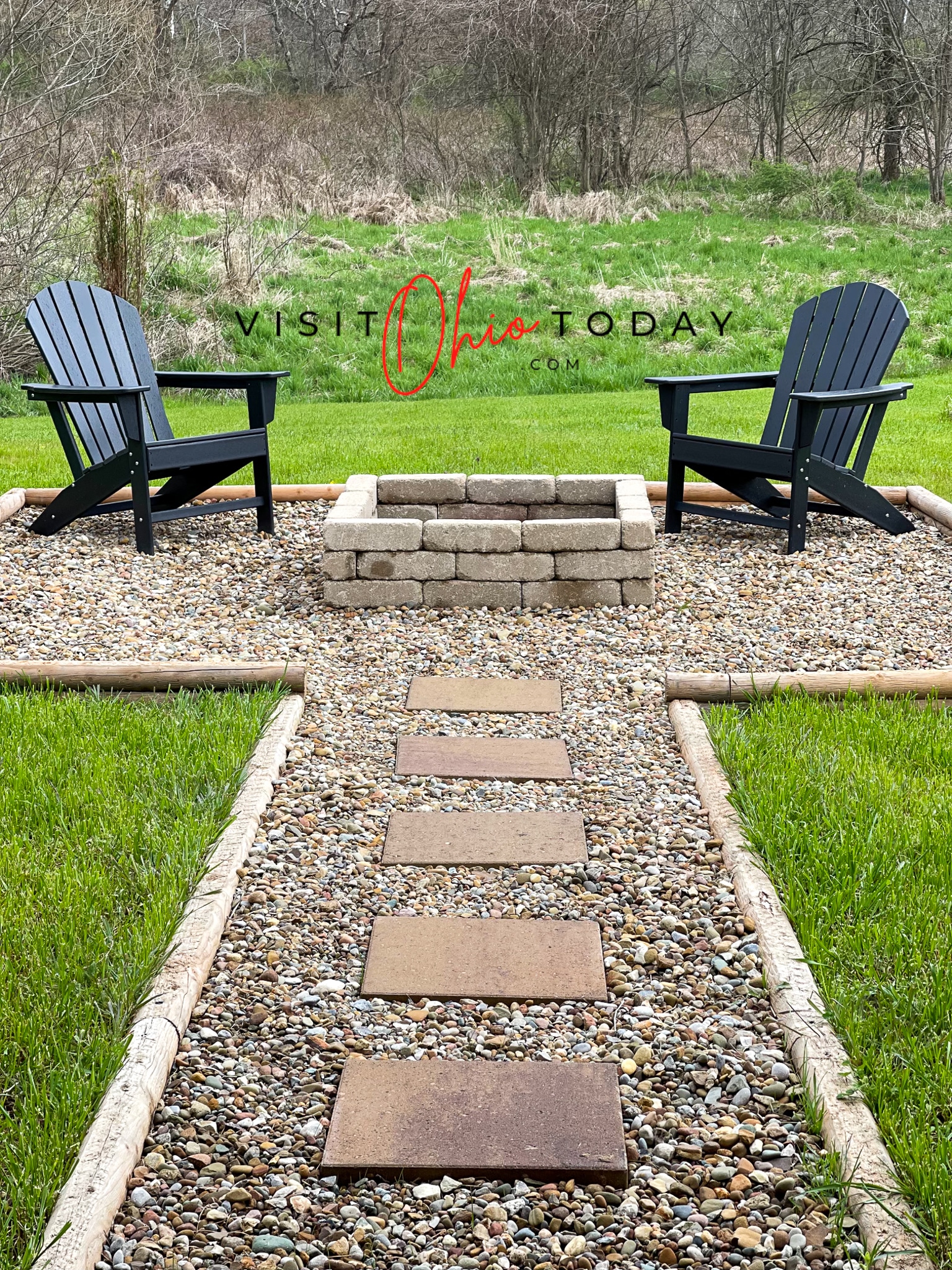 5 square stepping stones on gravel to a box fire pit with two black chairs on each side