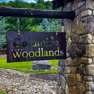 A close up of the black sign which reads Columbia Woodlands