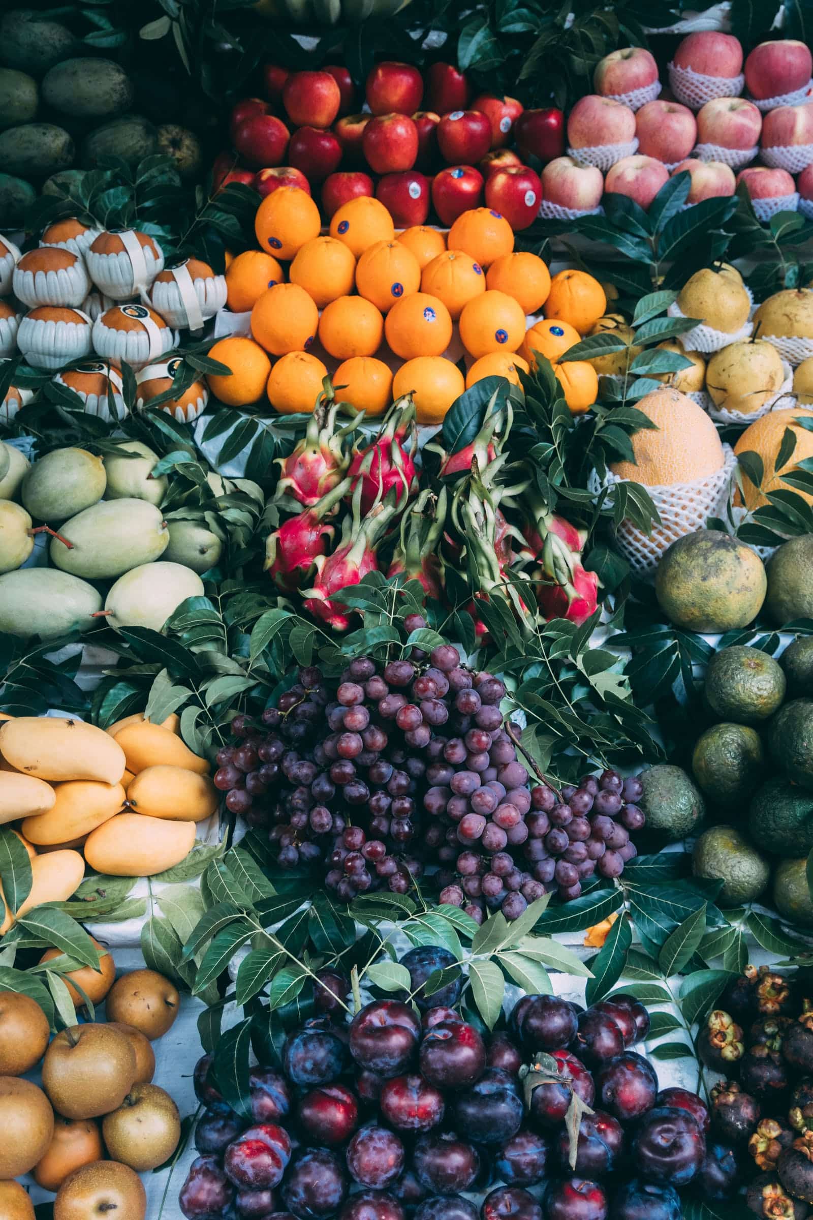 A photo of farm produce including oranges, grapes, apples and plums