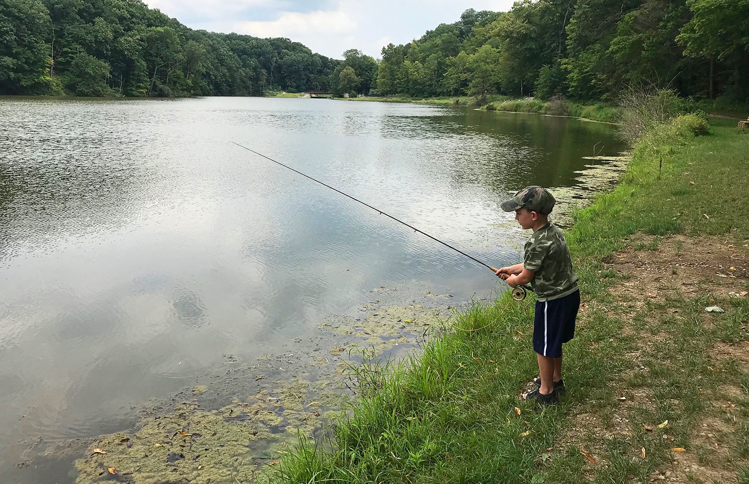 horizontal photo of a young boy fishing on the lake at Mt Gilead State Park
