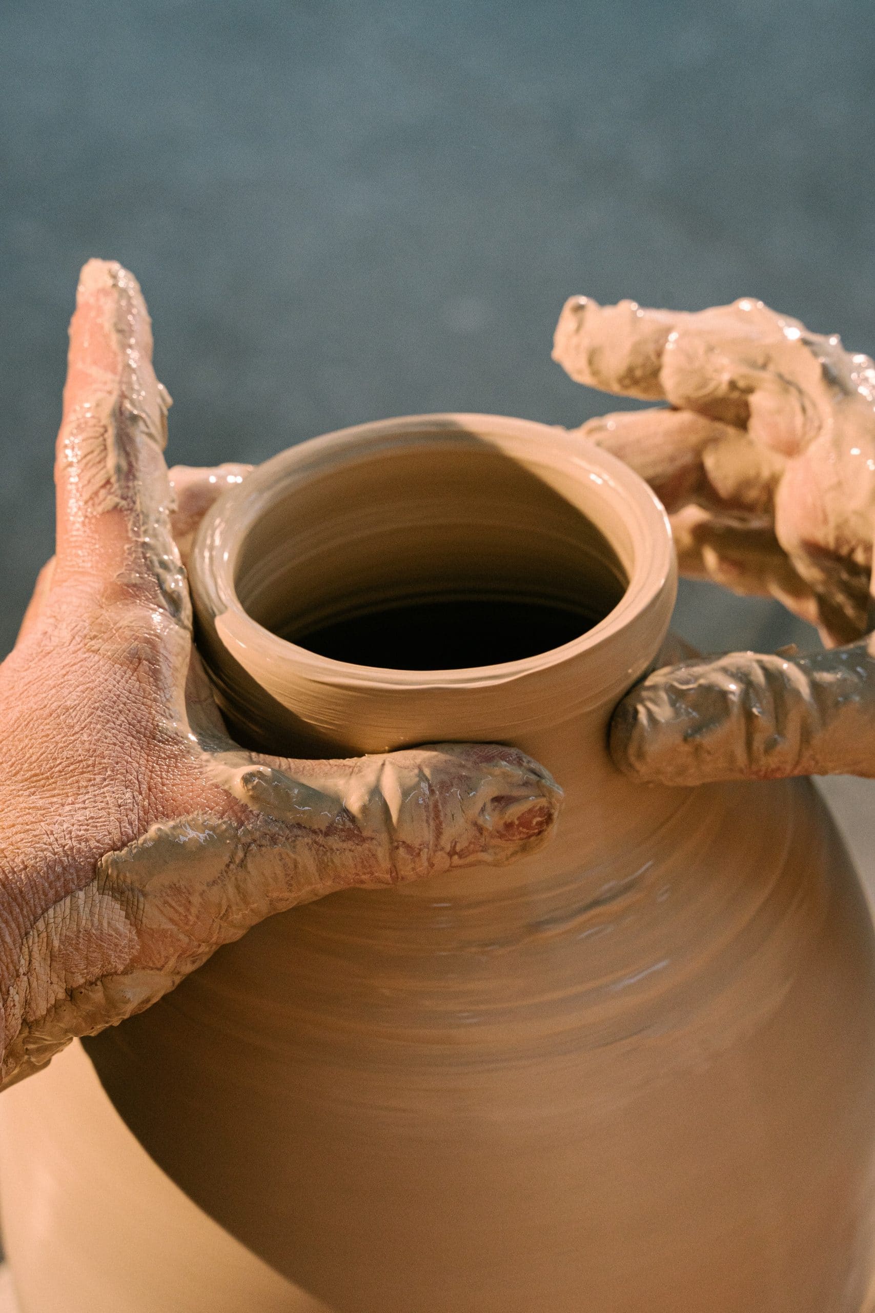 Two hands molding a pottery jug