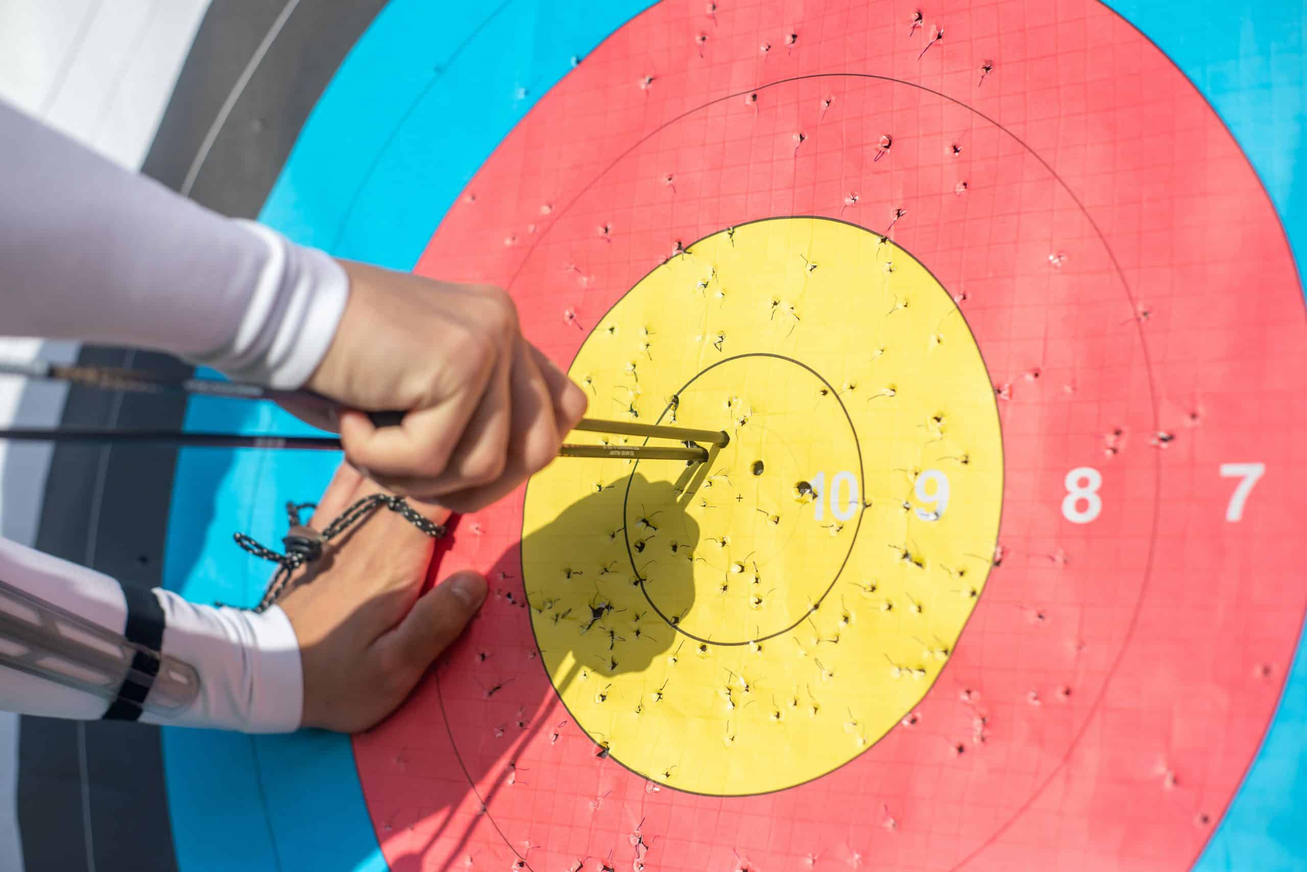 An archery target with arrows being pulled out from the centre