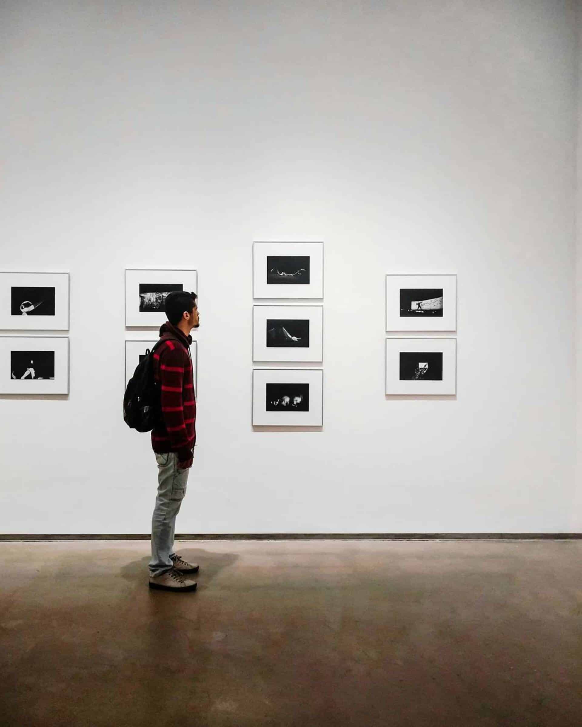 A male stood looking at are images on a white wall