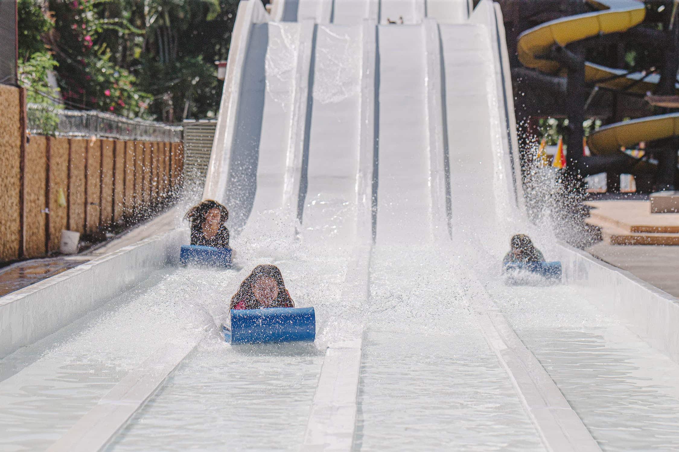 three people sliding down a water slide