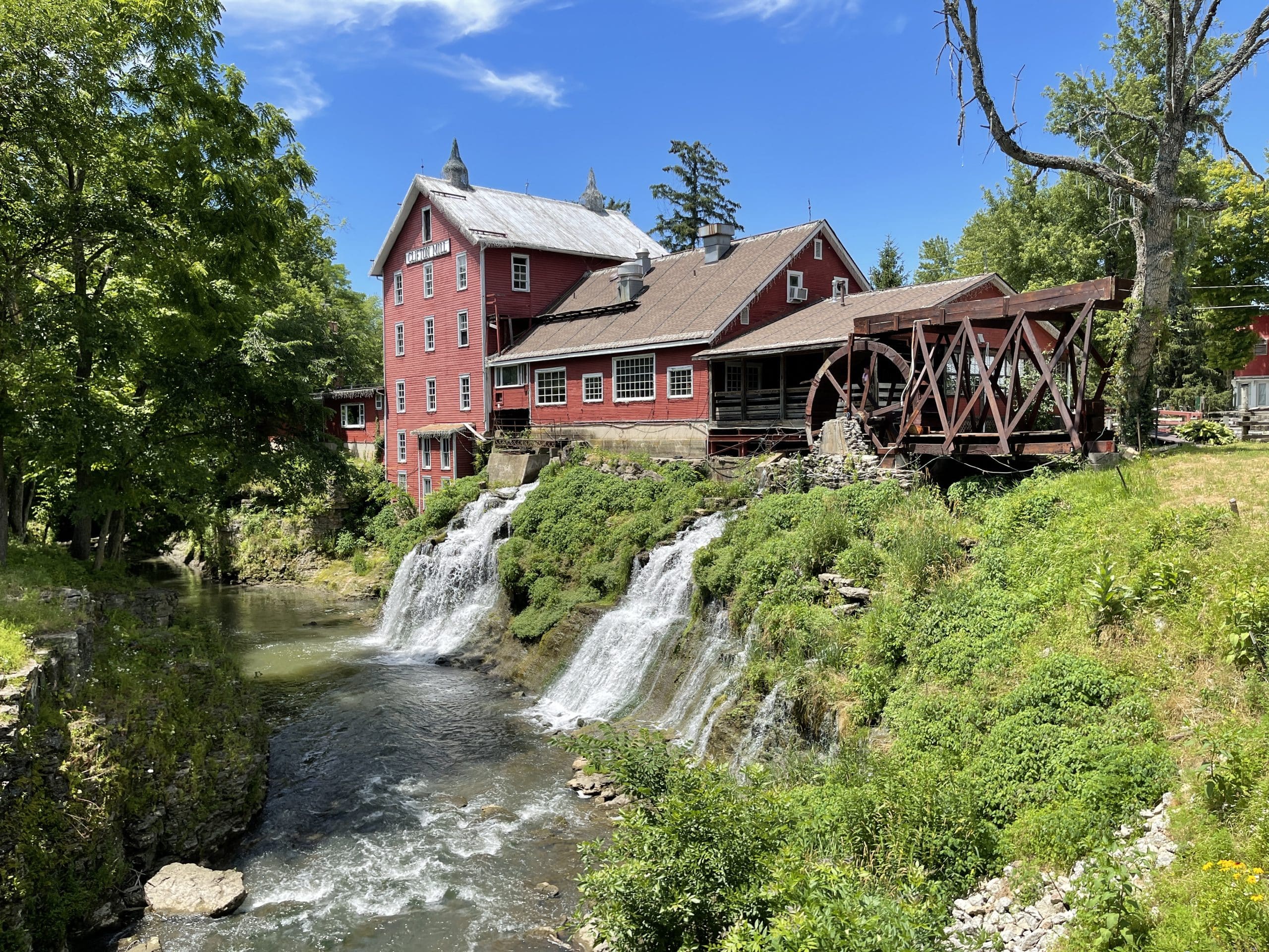 red mill named clifton mill with two waterfalls down into a river gorge