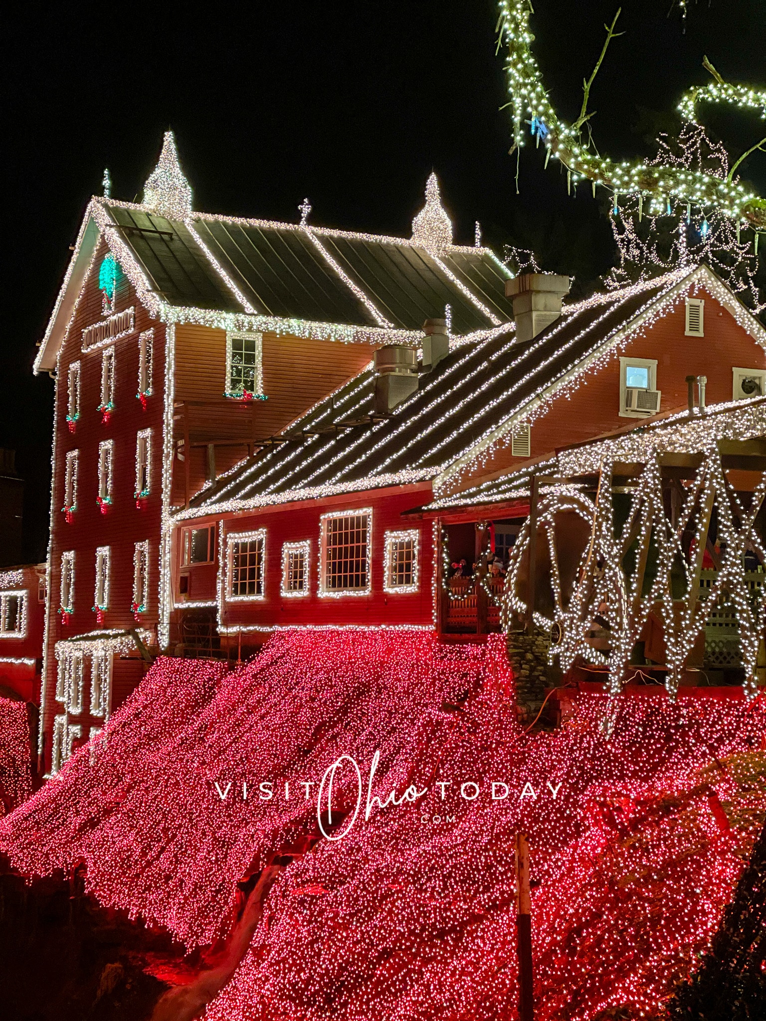 clifton mill on the creek side showing red building decorated with light of chrsitmas lights white and red ones