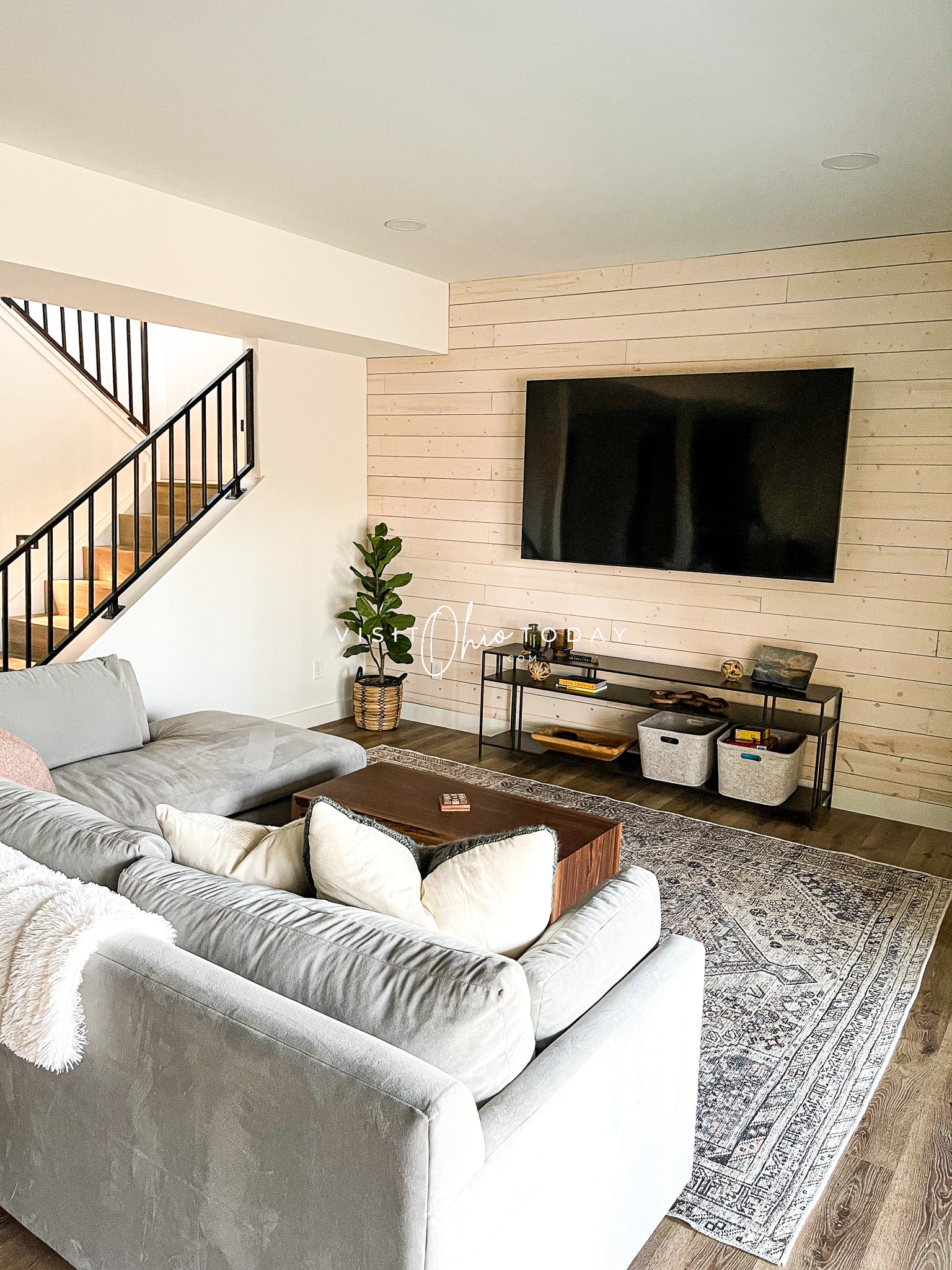 white walls of a tv room, giant black tv on wall, gray rug on floor, white couch will pillows and blankets Photo credit: Cindy Gordon of VisitOhioToday.com