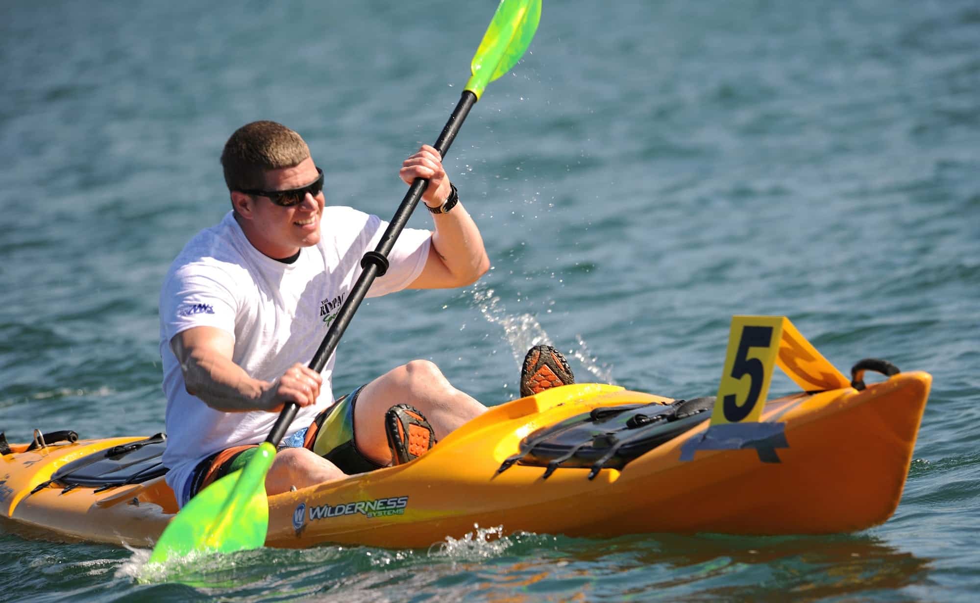 A male wearing a white t-shirt boating on a body of water