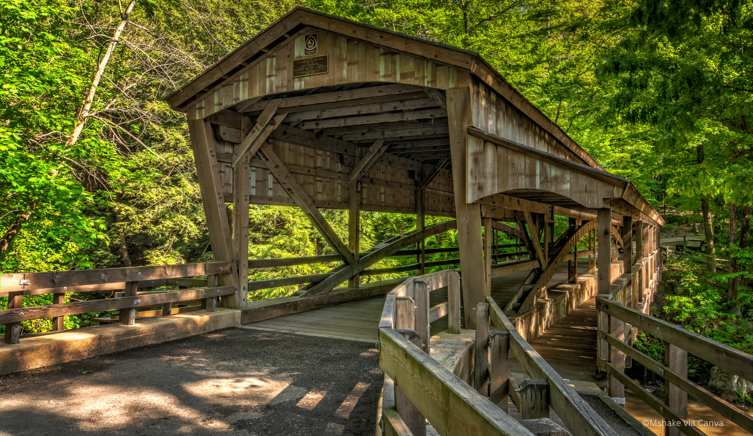 horizontal photo of the covered bridge at Lanterman's Mill. A wooden bridge with a lot of green trees around it. Image via Canva pro license
