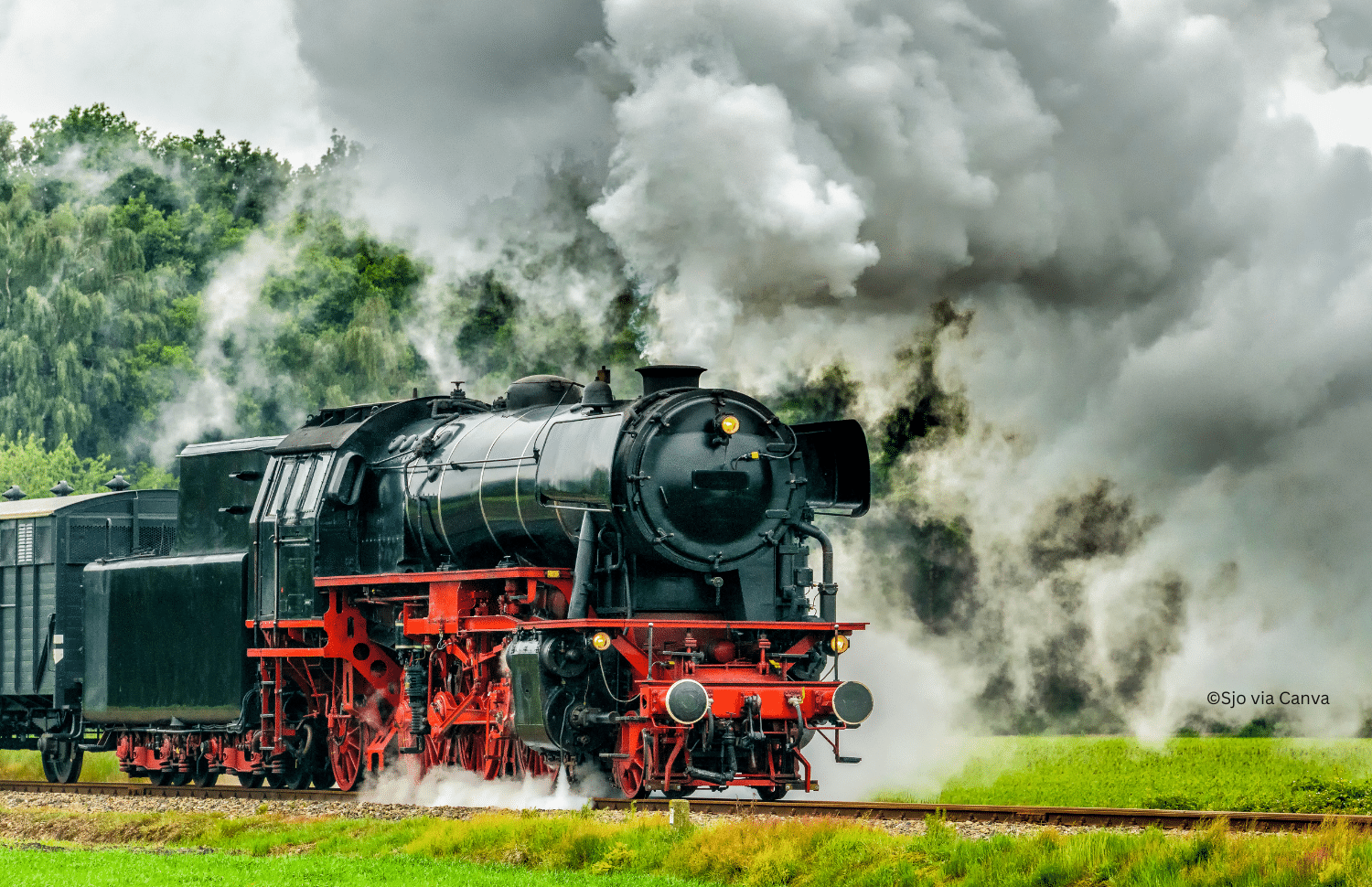 horizontal photo of a steam train traveling along the tracks on a summer day