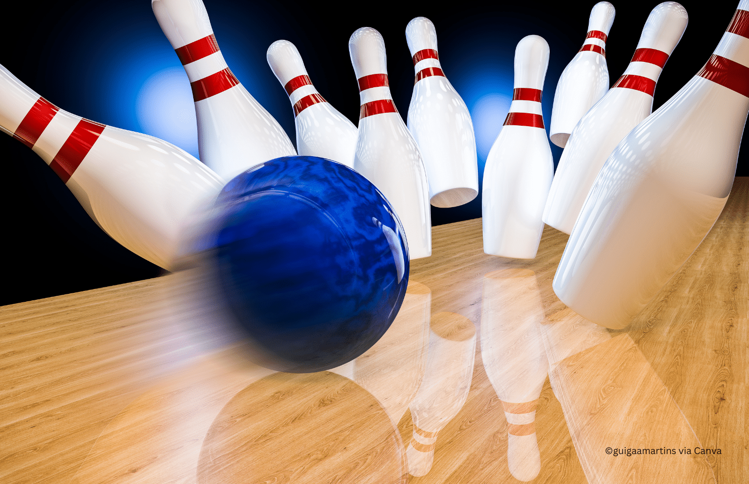 horizontal photo of a blue bowling ball striking white and red skittles