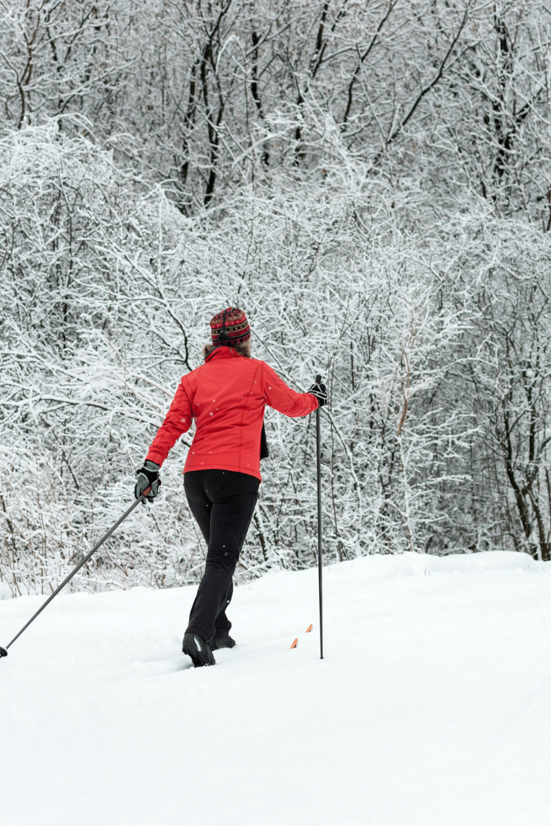 A person wearing a red jacket walking through a snowy forest