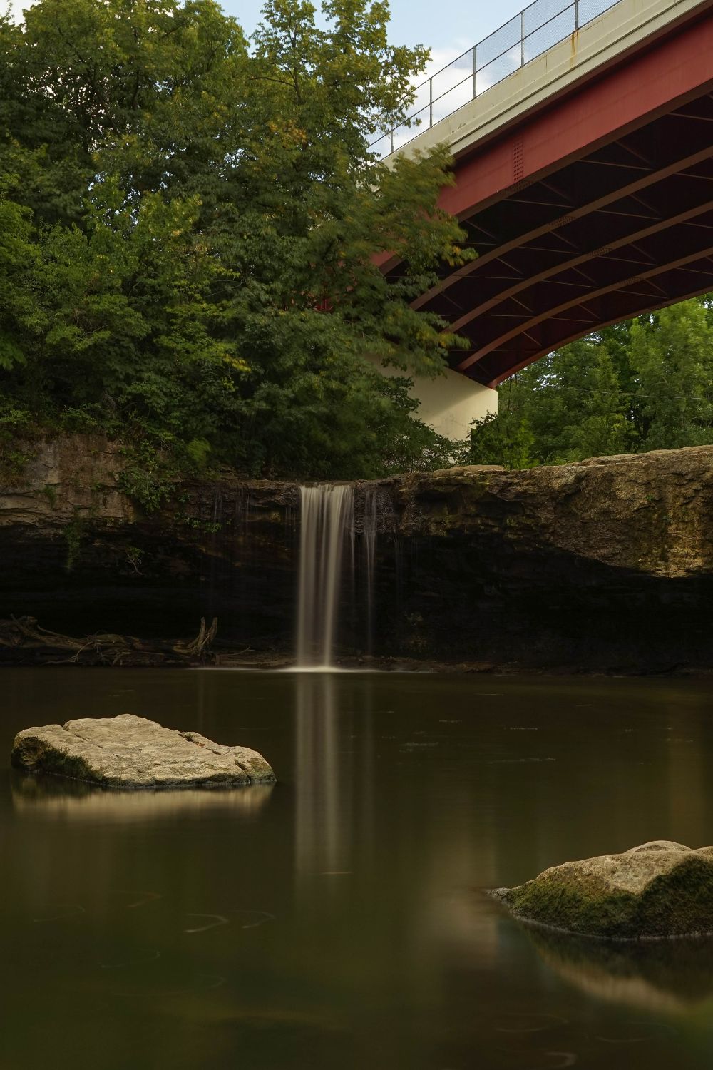 A photo of a waterfall underneath a red bridge. This photo is from Ludlow Falls