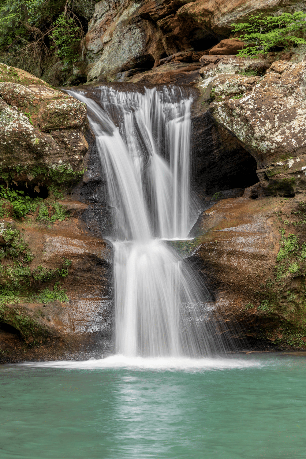 The waterfall at Old Man's Cave. Water cascading downwards over rocks into a blue green lagoon